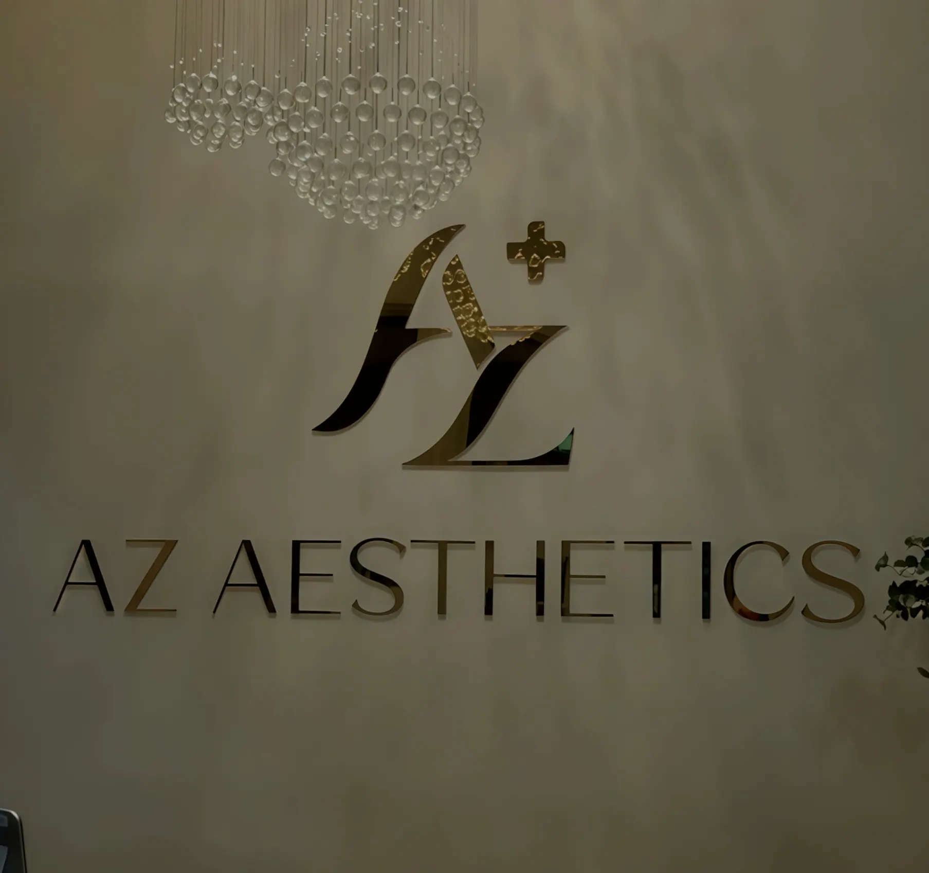 The AZ Aesthetics sign on the studio wall beneath a crystal pendant light